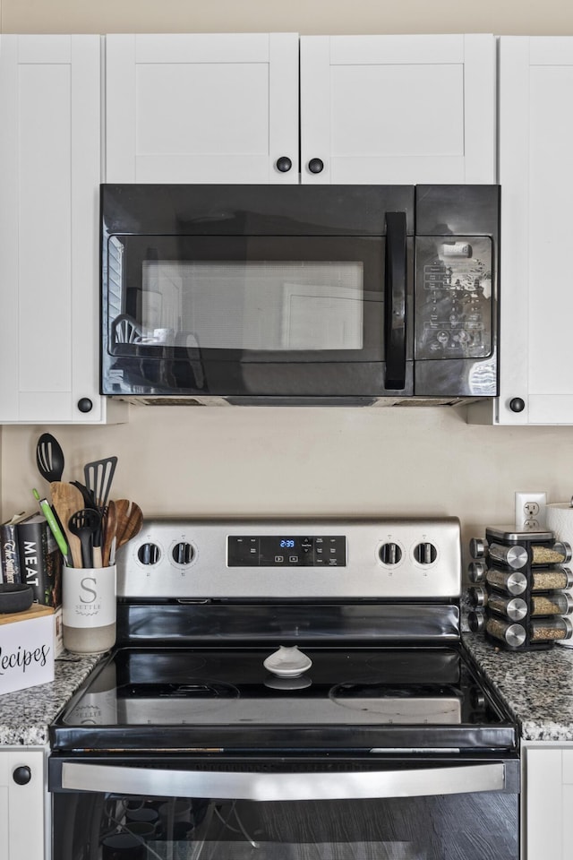 kitchen with stainless steel electric stove and white cabinetry