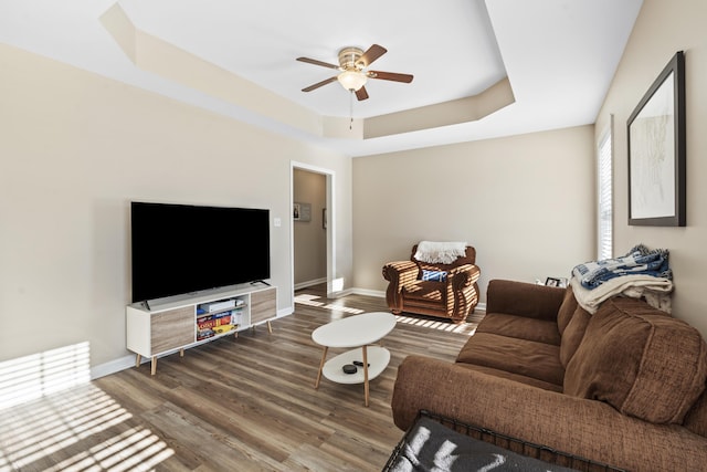 living room featuring hardwood / wood-style flooring, a tray ceiling, and ceiling fan