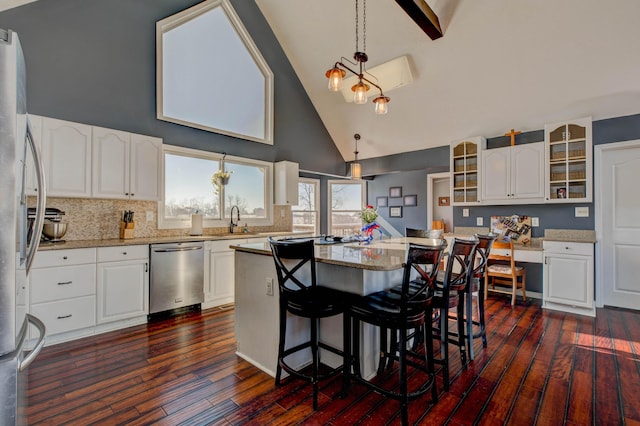 kitchen featuring high vaulted ceiling, white cabinetry, appliances with stainless steel finishes, and a center island