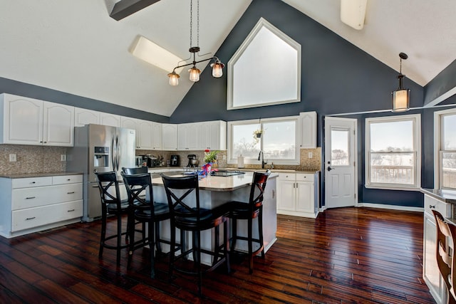 kitchen featuring decorative light fixtures, white cabinetry, tasteful backsplash, stainless steel fridge with ice dispenser, and high vaulted ceiling