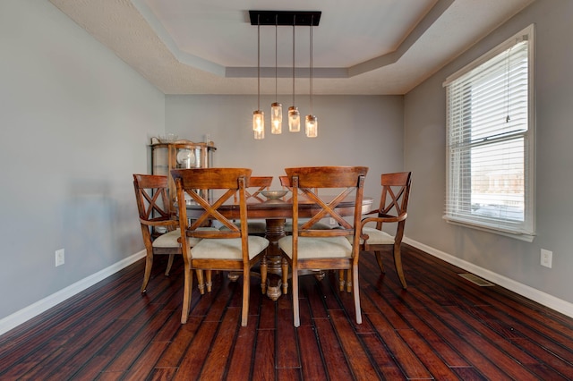 dining area with dark hardwood / wood-style flooring and a tray ceiling