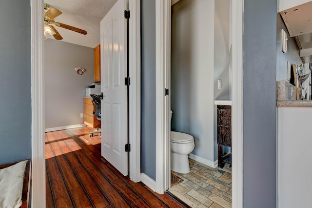 bathroom featuring ceiling fan, a textured ceiling, toilet, and wood-type flooring