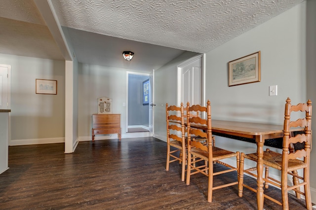 dining room featuring dark wood-type flooring and a textured ceiling