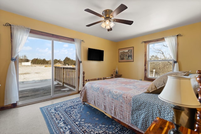 bedroom with multiple windows, access to outside, and ceiling fan