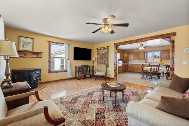 living room featuring ceiling fan, a wood stove, and light wood-type flooring