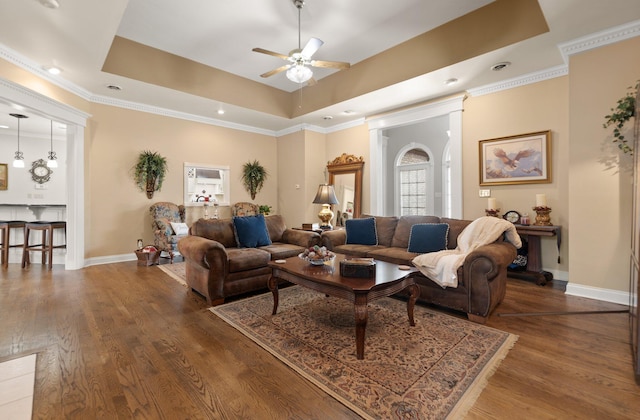 living room with crown molding, dark hardwood / wood-style floors, ceiling fan, and a tray ceiling