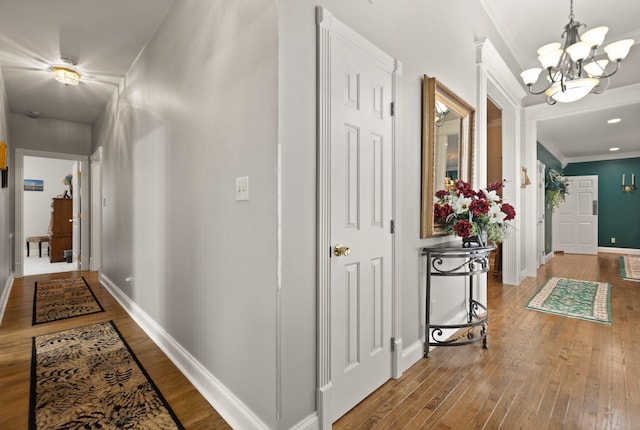 hallway with an inviting chandelier, ornamental molding, and hardwood / wood-style floors