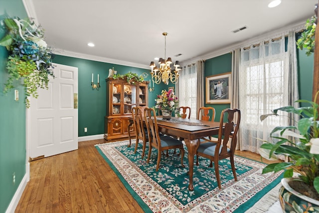 dining area with crown molding, wood-type flooring, a chandelier, and a wealth of natural light