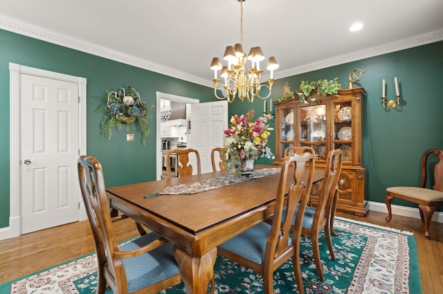 dining room with an inviting chandelier, crown molding, and hardwood / wood-style floors