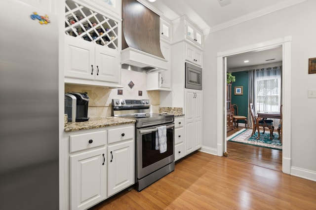 kitchen with premium range hood, appliances with stainless steel finishes, tasteful backsplash, light hardwood / wood-style floors, and white cabinets