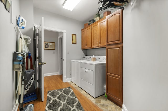 laundry area featuring cabinets, independent washer and dryer, and light hardwood / wood-style flooring