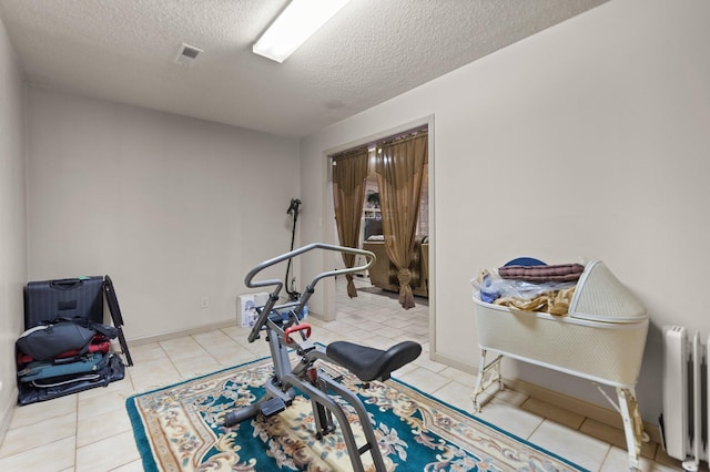 exercise room featuring radiator, light tile patterned floors, and a textured ceiling