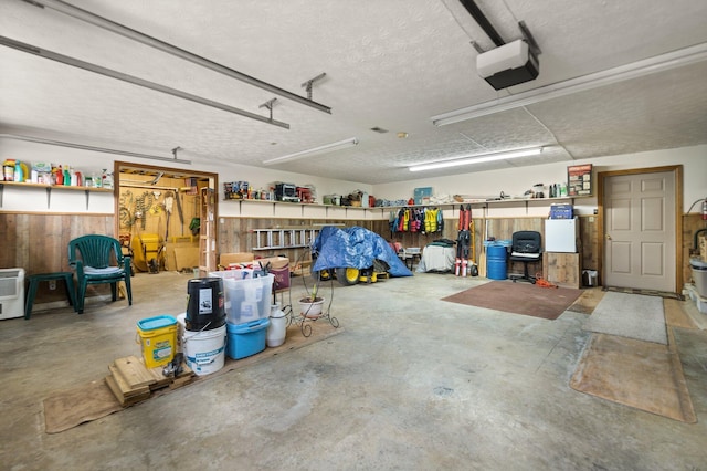 garage with a garage door opener and wood walls