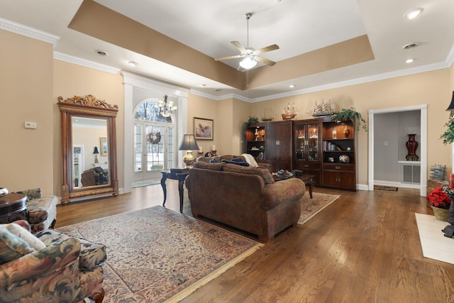 living room featuring a tray ceiling, ceiling fan with notable chandelier, ornamental molding, and dark hardwood / wood-style floors