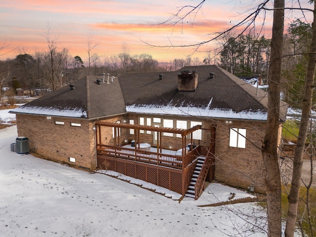 snow covered property featuring central AC unit and a deck