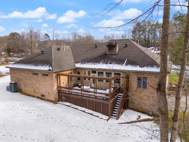 snow covered rear of property with a wooden deck and central AC