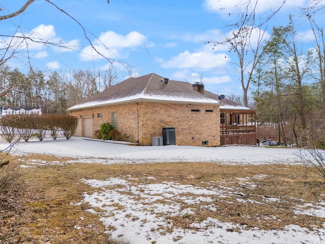 view of snowy exterior featuring a garage and central air condition unit