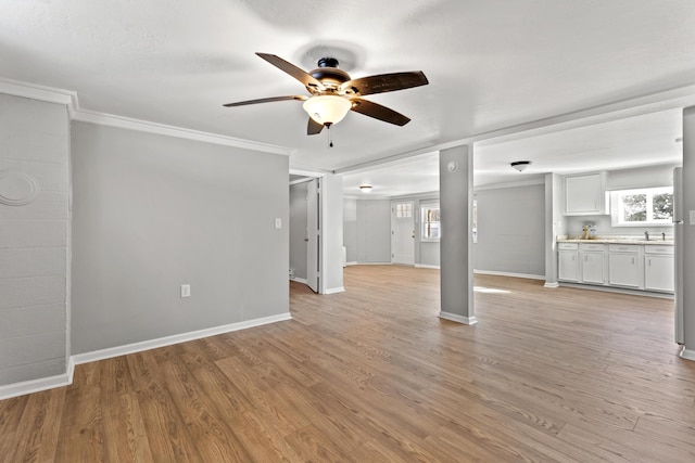 unfurnished living room featuring light wood-type flooring, ceiling fan, ornamental molding, and sink