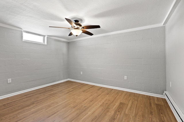 spare room featuring crown molding, ceiling fan, a baseboard heating unit, hardwood / wood-style flooring, and brick wall