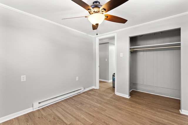 unfurnished bedroom with baseboard heating, hardwood / wood-style floors, a closet, ornamental molding, and ceiling fan