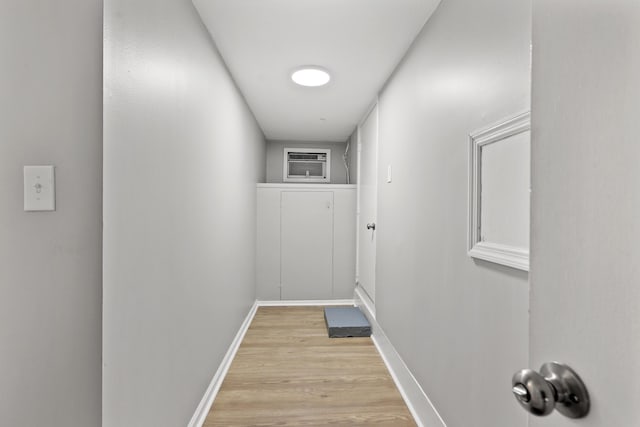 corridor with an AC wall unit and light hardwood / wood-style flooring