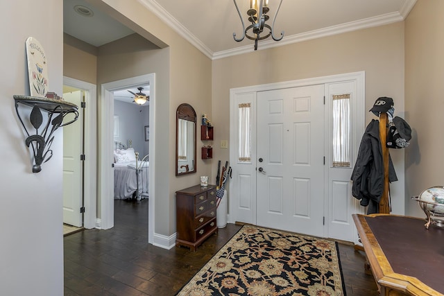 foyer entrance with dark wood-type flooring, a chandelier, crown molding, and baseboards