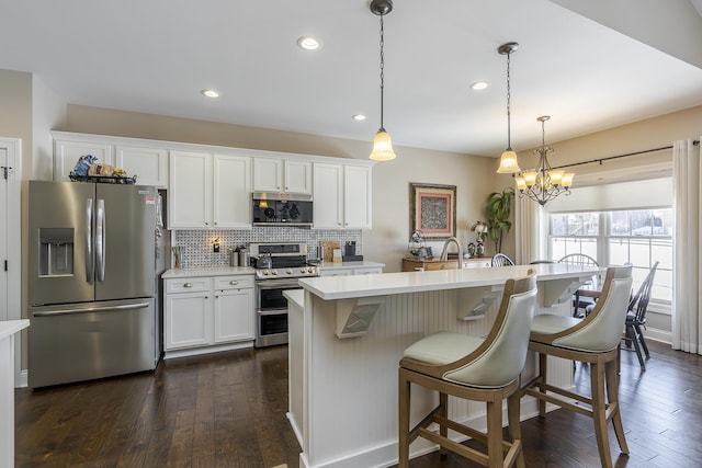 kitchen featuring stainless steel appliances, light countertops, dark wood-type flooring, and decorative backsplash