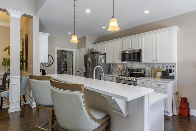 kitchen featuring stainless steel appliances, dark wood-style flooring, white cabinets, backsplash, and ornate columns