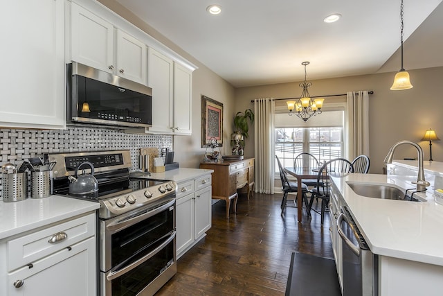 kitchen featuring a notable chandelier, stainless steel appliances, tasteful backsplash, white cabinetry, and a sink