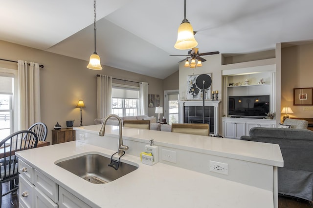 kitchen featuring open floor plan, light countertops, a tiled fireplace, and a sink