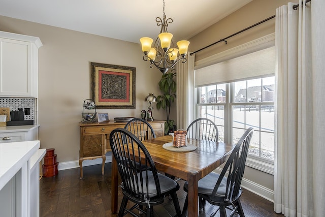 dining space with dark wood-style flooring, an inviting chandelier, and baseboards