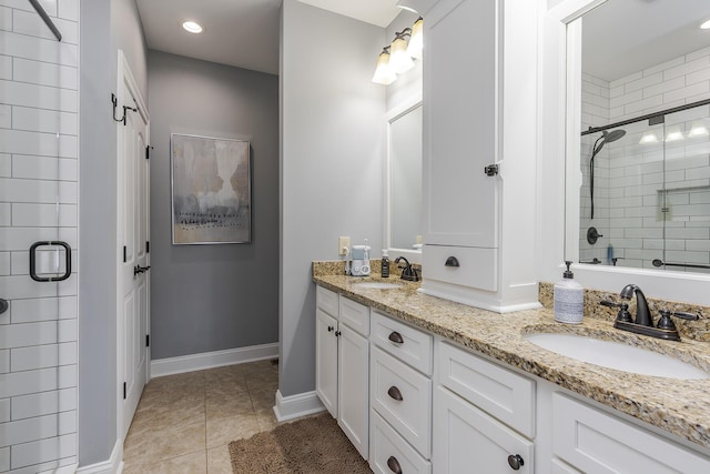 full bathroom featuring double vanity, a shower stall, a sink, and tile patterned floors