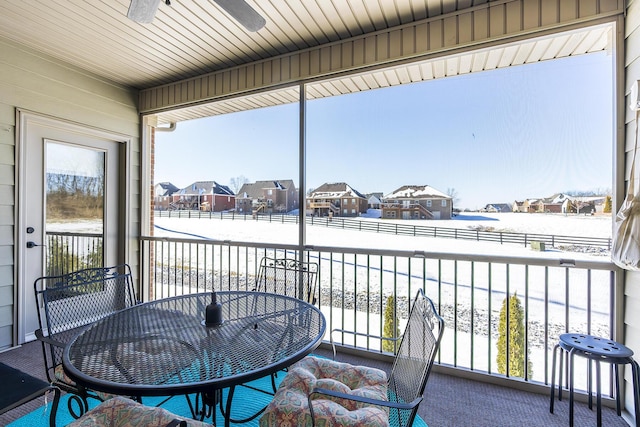 sunroom / solarium with a residential view and ceiling fan