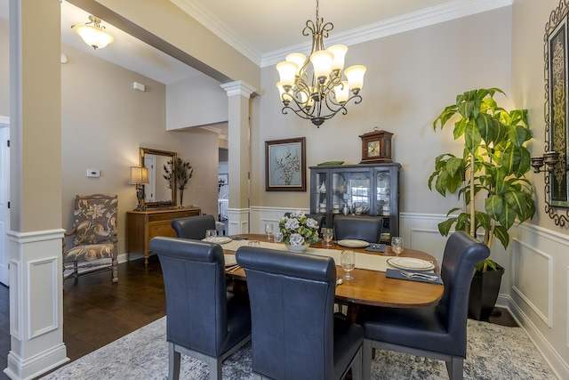 dining area featuring decorative columns, ornamental molding, wainscoting, wood finished floors, and a chandelier