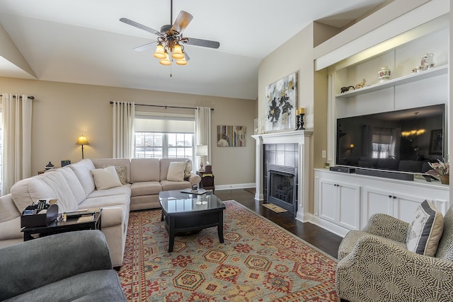 living room featuring built in features, dark wood finished floors, a ceiling fan, a tiled fireplace, and lofted ceiling