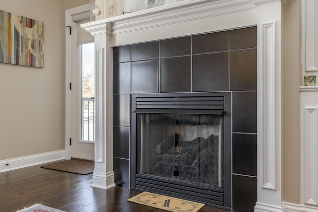 room details with a tile fireplace, baseboards, and wood finished floors