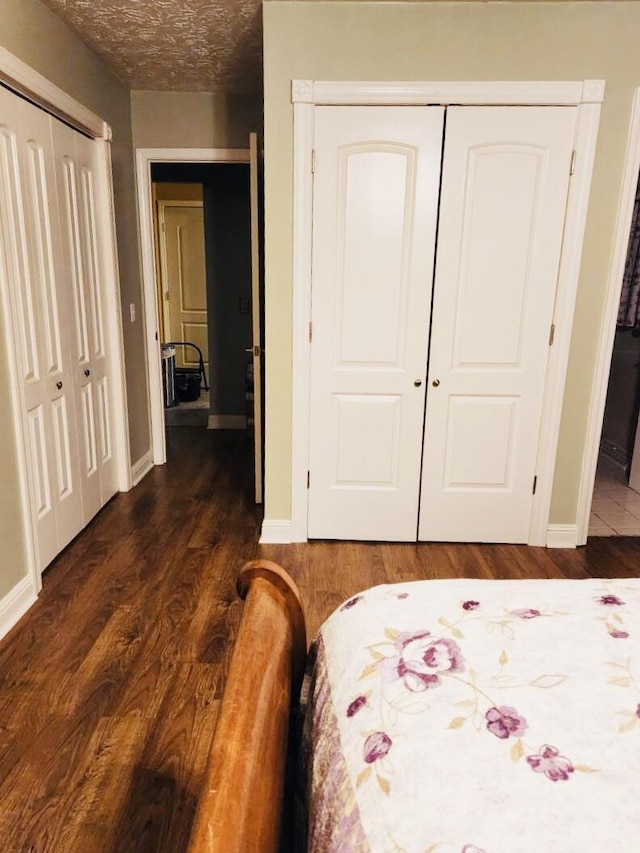 bedroom with a textured ceiling, dark hardwood / wood-style flooring, and a closet