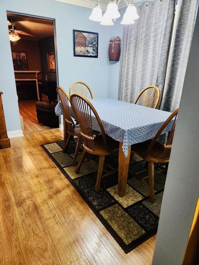 dining space featuring ceiling fan with notable chandelier and light hardwood / wood-style flooring