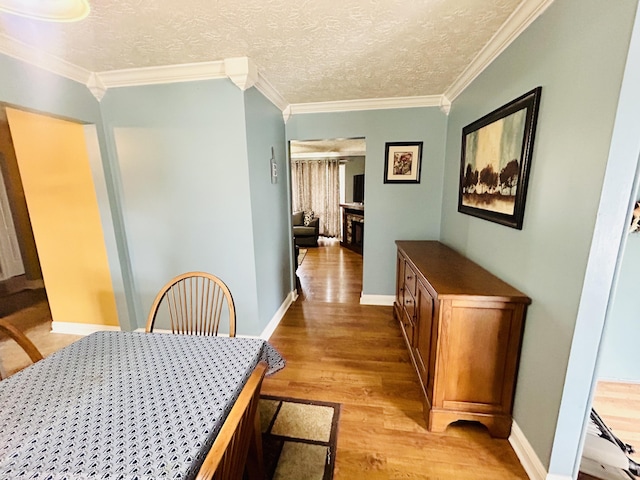 dining room featuring ornamental molding, light hardwood / wood-style floors, and a textured ceiling