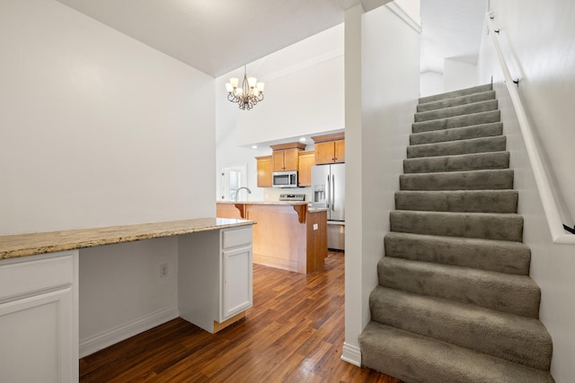 staircase featuring a notable chandelier, hardwood / wood-style flooring, and a high ceiling