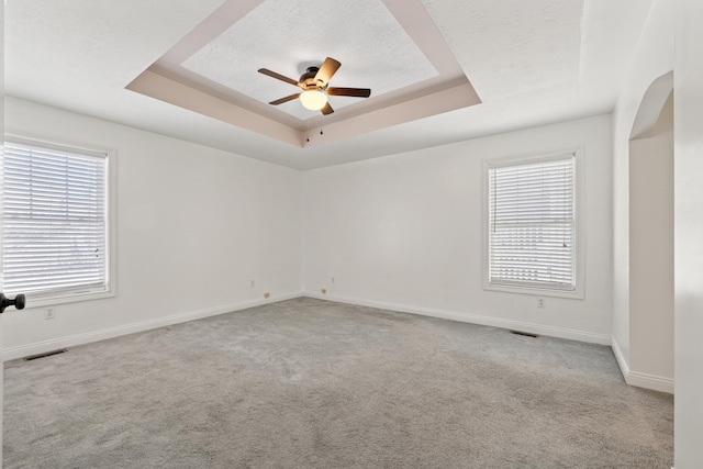 carpeted spare room featuring ceiling fan and a tray ceiling