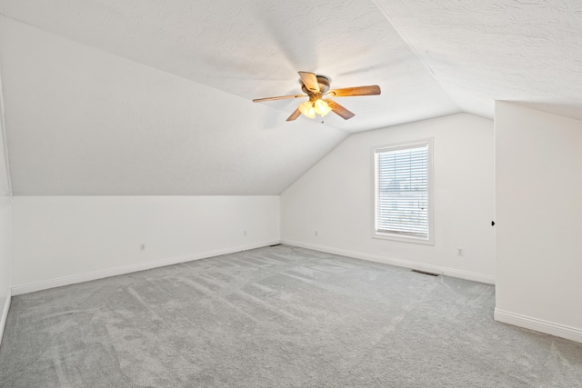 bonus room with light carpet, vaulted ceiling, ceiling fan, and a textured ceiling