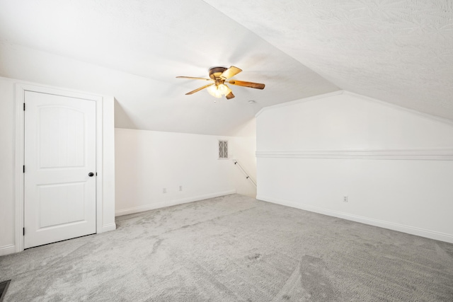 bonus room featuring vaulted ceiling, ceiling fan, a textured ceiling, and light carpet