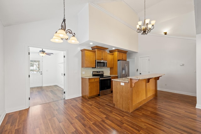 kitchen with appliances with stainless steel finishes, decorative backsplash, a kitchen breakfast bar, an inviting chandelier, and pendant lighting