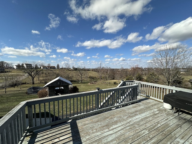 deck featuring a storage shed, a rural view, and a lawn