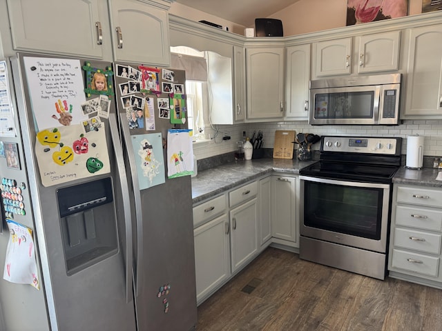 kitchen with vaulted ceiling, appliances with stainless steel finishes, dark hardwood / wood-style floors, white cabinets, and backsplash