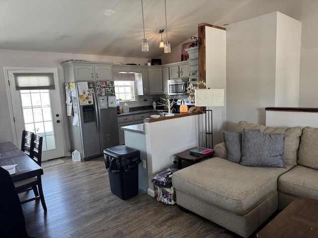 kitchen featuring lofted ceiling, appliances with stainless steel finishes, hanging light fixtures, hardwood / wood-style floors, and decorative backsplash