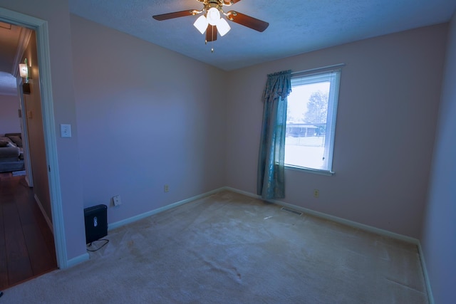 empty room featuring ceiling fan, a textured ceiling, and carpet flooring