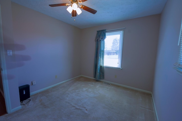 carpeted spare room featuring ceiling fan and a textured ceiling