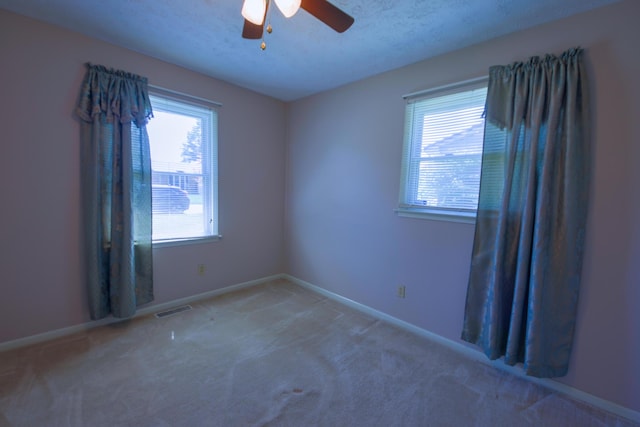 carpeted empty room with ceiling fan and a textured ceiling